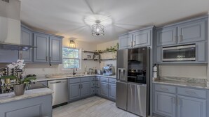 Une cuisine moderne avec des armoires grises, des appareils en acier inoxydable et un ventilateur de plafond.