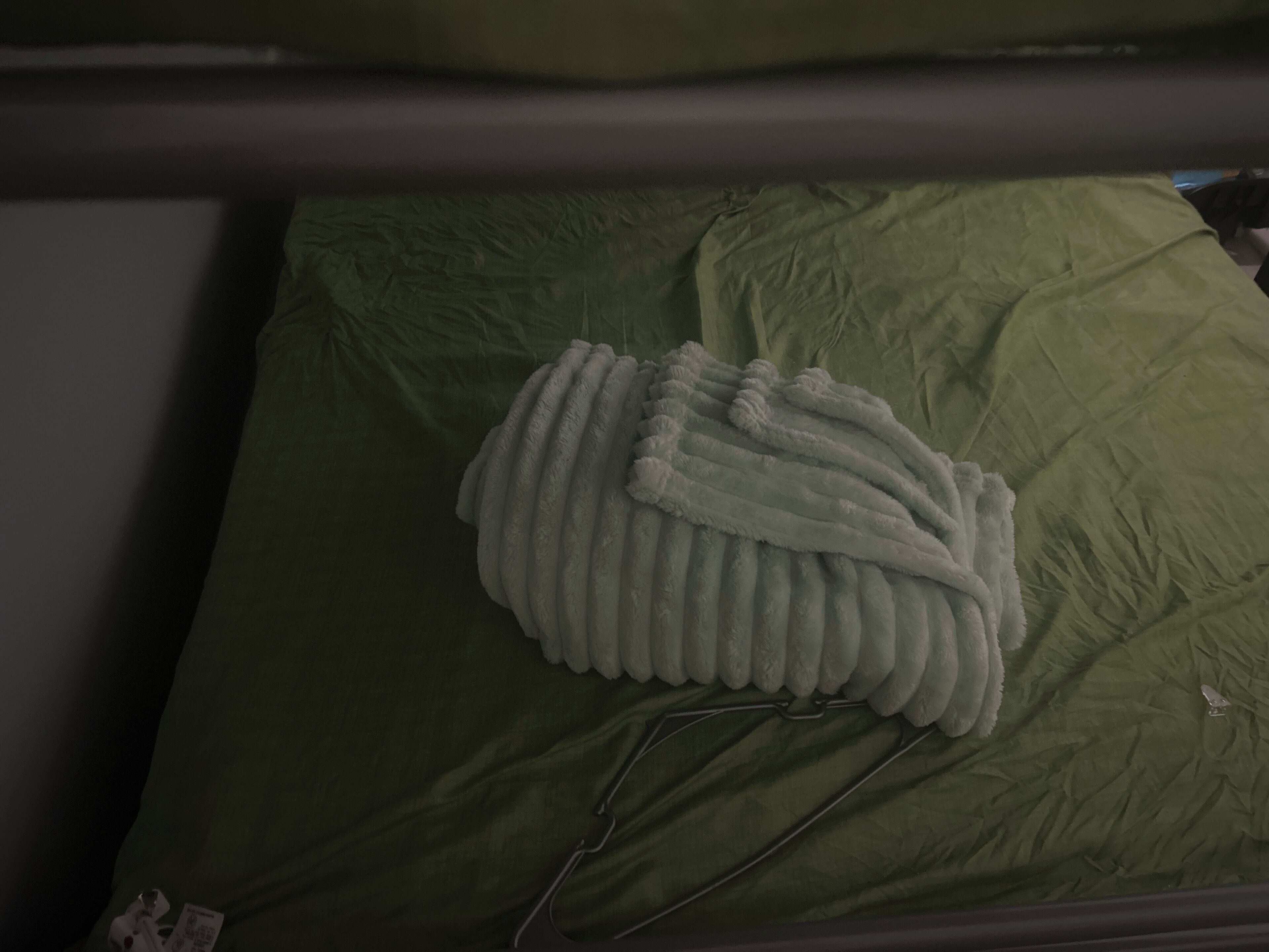 A bed with a green sheet and a white blanket.