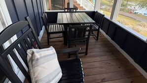 A covered outdoor seating area with a wooden deck, a table, and chairs. - Waterfront Paddles & Pours Cottage on Claytor Lake (Hiwassee)