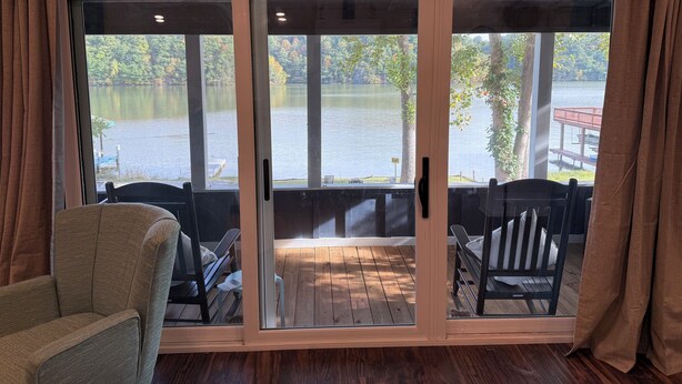 A room with a large sliding glass door leading to a wooden deck overlooking a lake. - Waterfront Paddles & Pours Cottage on Claytor Lake (Hiwassee)