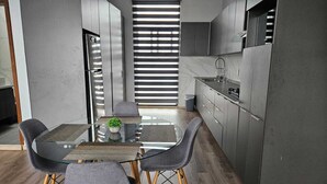 A modern kitchen with a glass dining table, grey chairs, and a built-in oven. - Mia La Perla Apartment, very close to La Perla District, Plaza del Sol, Expo GDL (Zapopan)