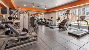 A gym with various exercise machines, large windows, and a tiled floor. - Deep Ellum-Sleeps 5-Balcony-Pool-Medical District (Dallas)
