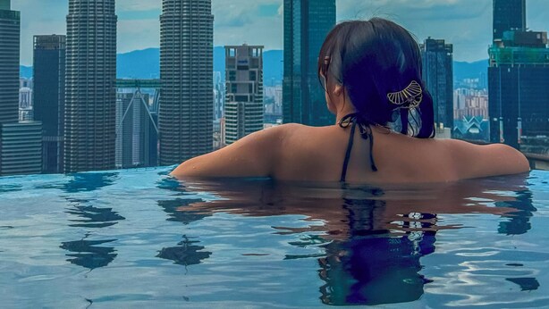 A person in a swimming pool with a cityscape in the background.