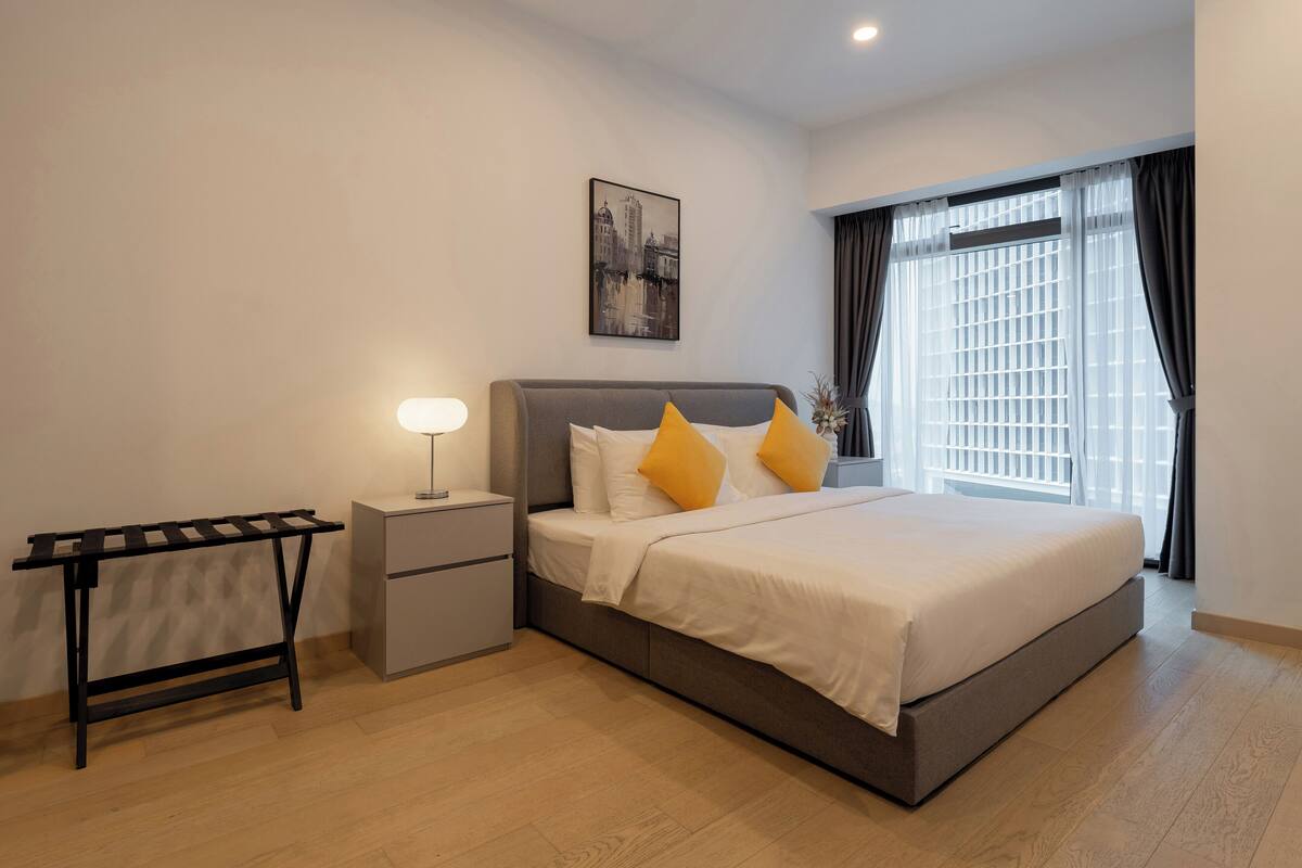 Un dormitorio moderno con cama, mesita de noche, lámpara y un cuadro de un paisaje urbano en la pared.