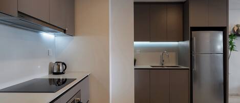 Una cocina moderna con estufa integrada, refrigerador de acero inoxidable y un lavamanos.