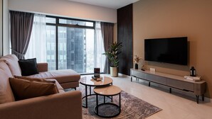 A modern living room with a sofa, coffee table, TV, and a large window with curtains.