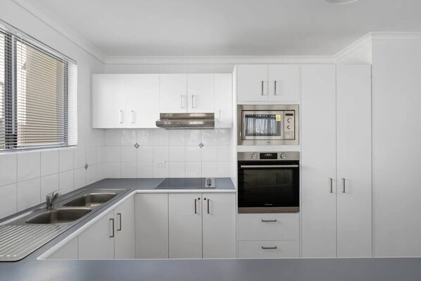 Eine moderne Küche mit weißen Schränken, einer Edelstahl-Dunstabzugshaube, einer Mikrowelle und einem Backofen.