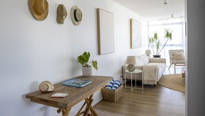 Una sala de estar con una mesa de madera, un sofá, una silla, una lámpara y una planta en maceta.