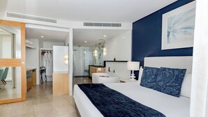 A modern bedroom with a large bed, a bedside table, a mirror, and a view into the bathroom.