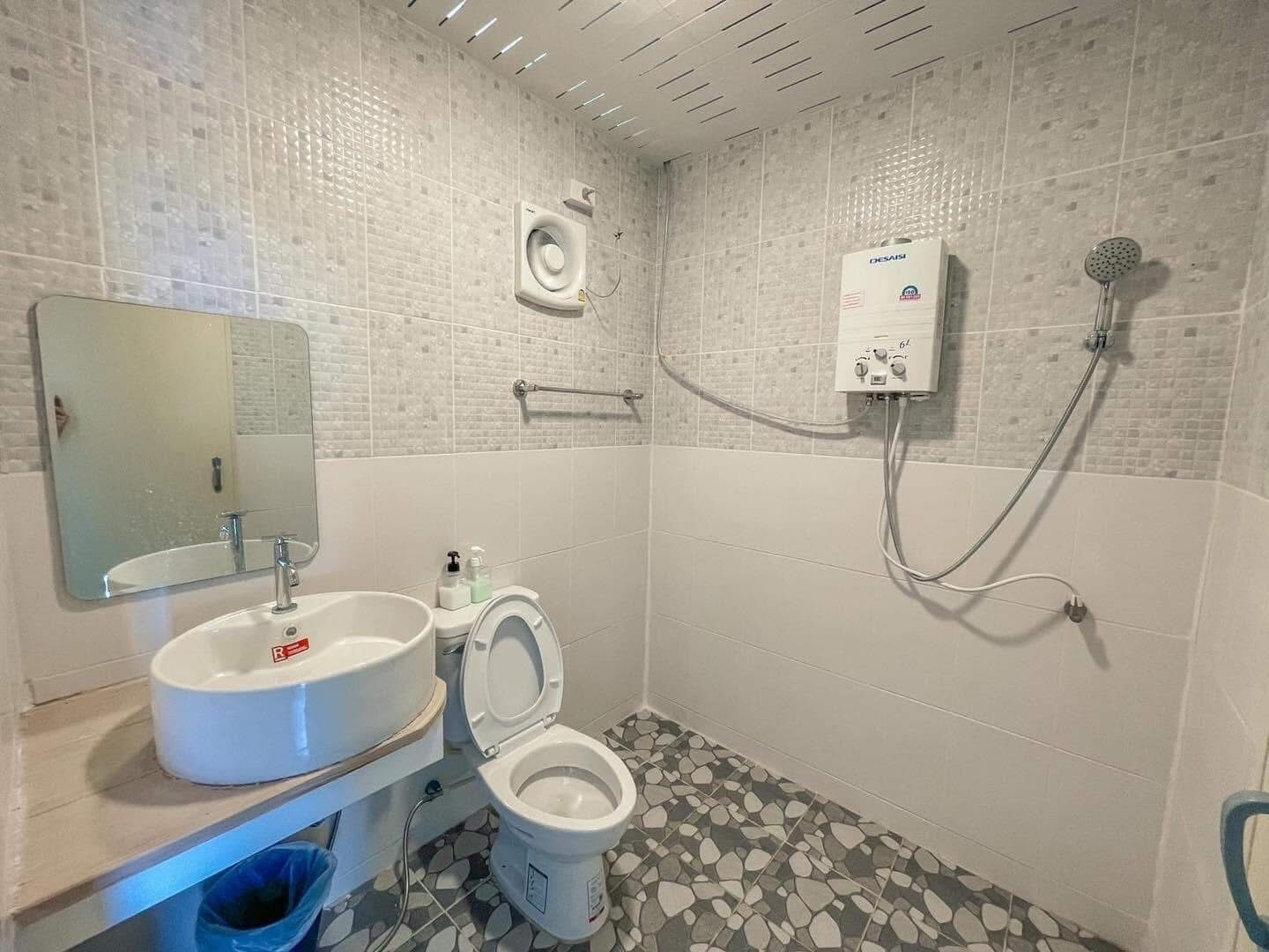 A bathroom with a white sink, toilet, and shower.