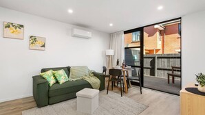 Un salon moderne avec un canapé vert, une petite table et un coin repas.
