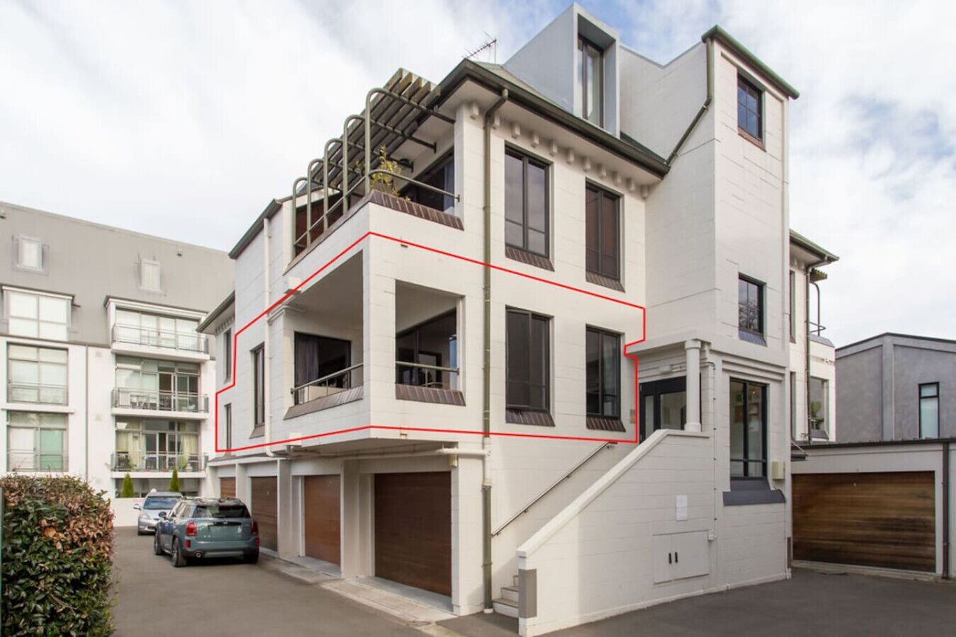 A multi-story residential building with a balcony on the second floor, a garage, and a staircase leading to the upper floors.