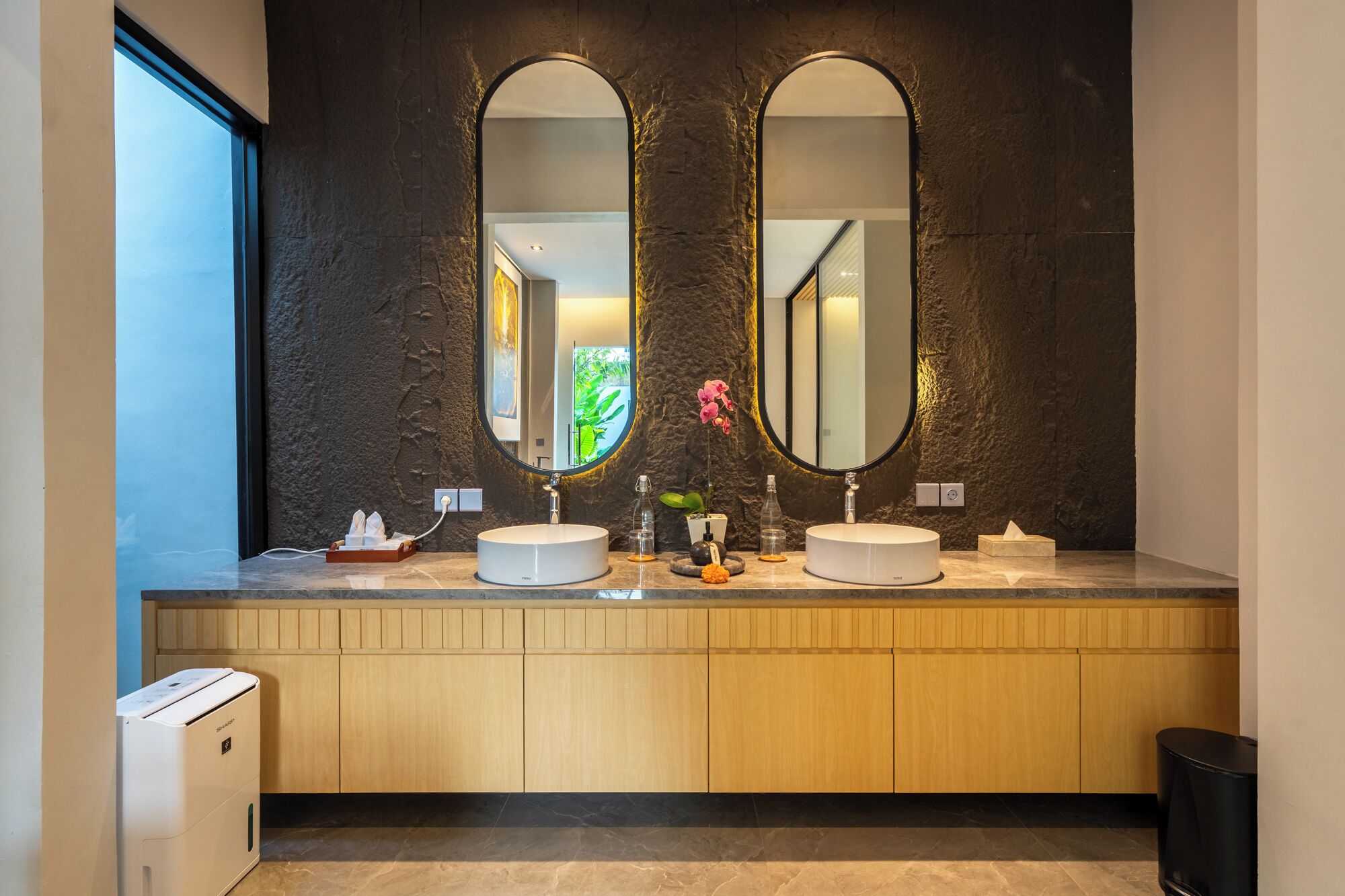 A modern bathroom with two sinks, large mirrors, and a wooden vanity.