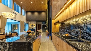 Una cocina moderna con encimera de mármol, armarios de madera y salpicadero negro.