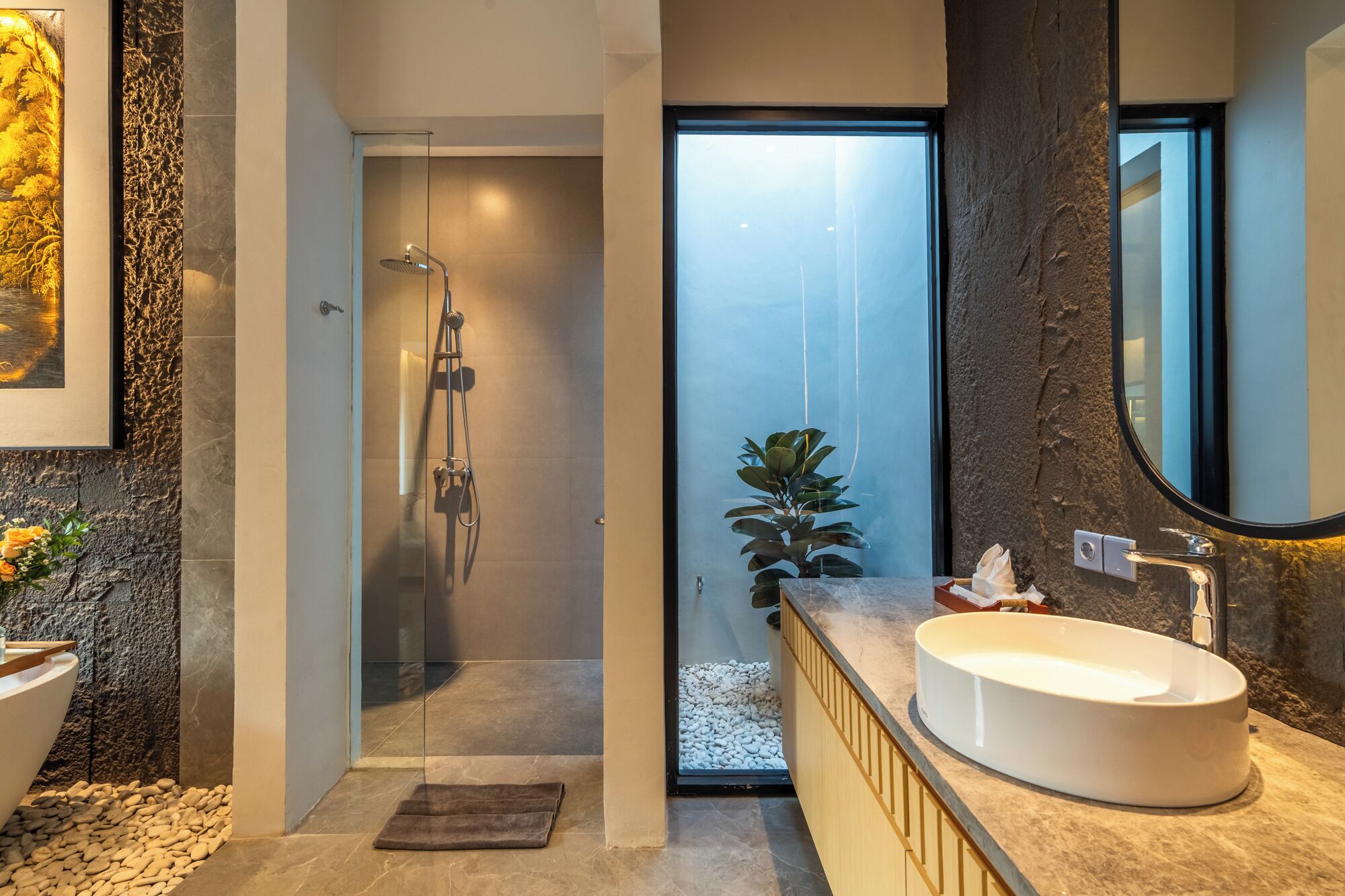 A modern bathroom with a large sink, a shower, and a mirror.