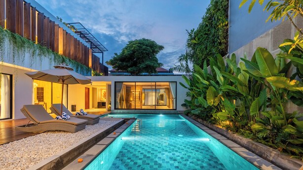 Un área de piscina moderna con piscina con azulejos, sillas de descanso y un muelle de madera.