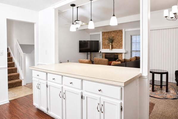 A modern kitchen with white cabinetry, a beige countertop, and pendant lighting.