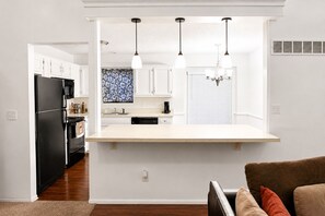A modern kitchen with white cabinetry, a black refrigerator, and a central island with pendant lighting.