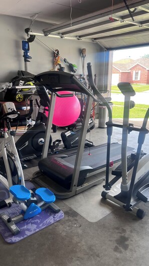 A home gym with a treadmill, elliptical, and exercise balls.