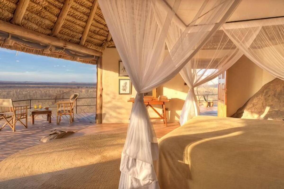 Ein Zimmer mit einem Bett, einem Tisch, Stühlen und Blick auf die Landschaft.