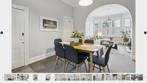 A dining area with a wooden table, dark chairs, and a hanging light fixture. - Villa on Rattray (Dunedin)