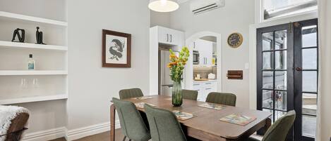 A dining area with a wooden table, six chairs, a vase with flowers, and a white pendant light.