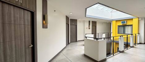 A modern interior with a central island, a skylight, and a yellow accent wall.