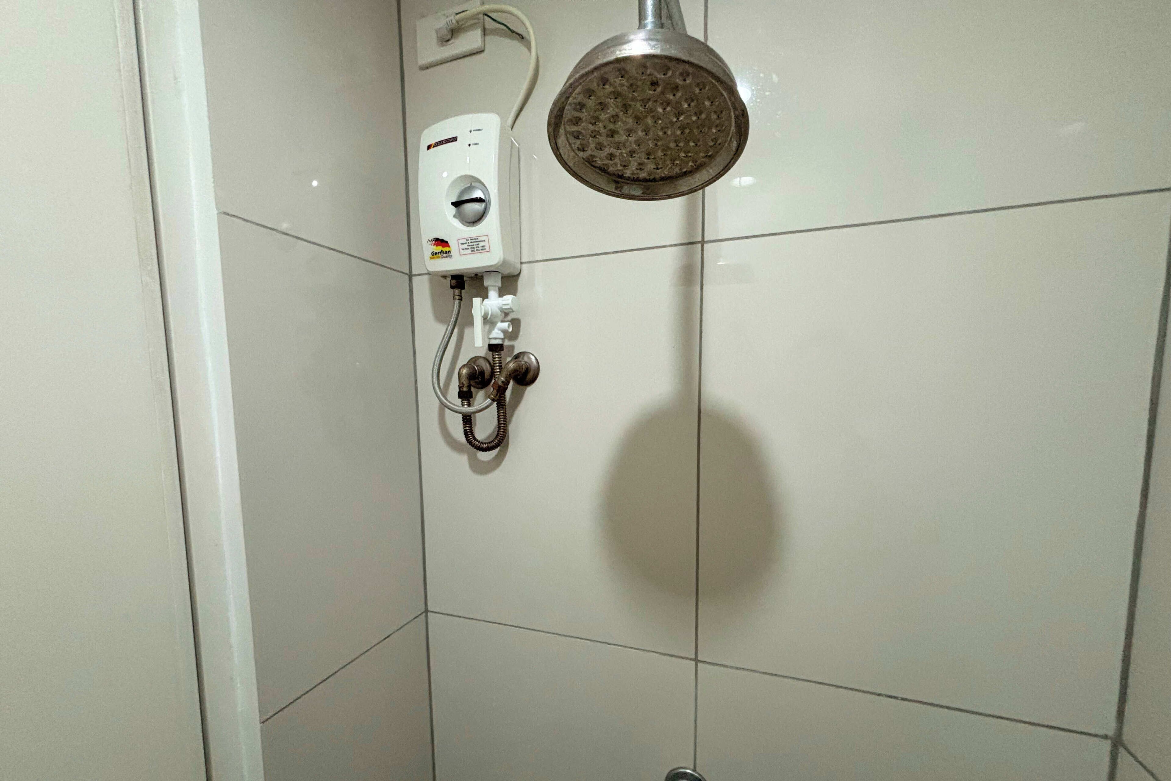 A shower with a handheld showerhead and a wall-mounted control panel.