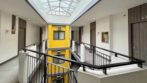 A modern interior with a central yellow column, a glass ceiling, and a staircase with black railings. - Casa Lily Hotel Quezon City (Quezon City)