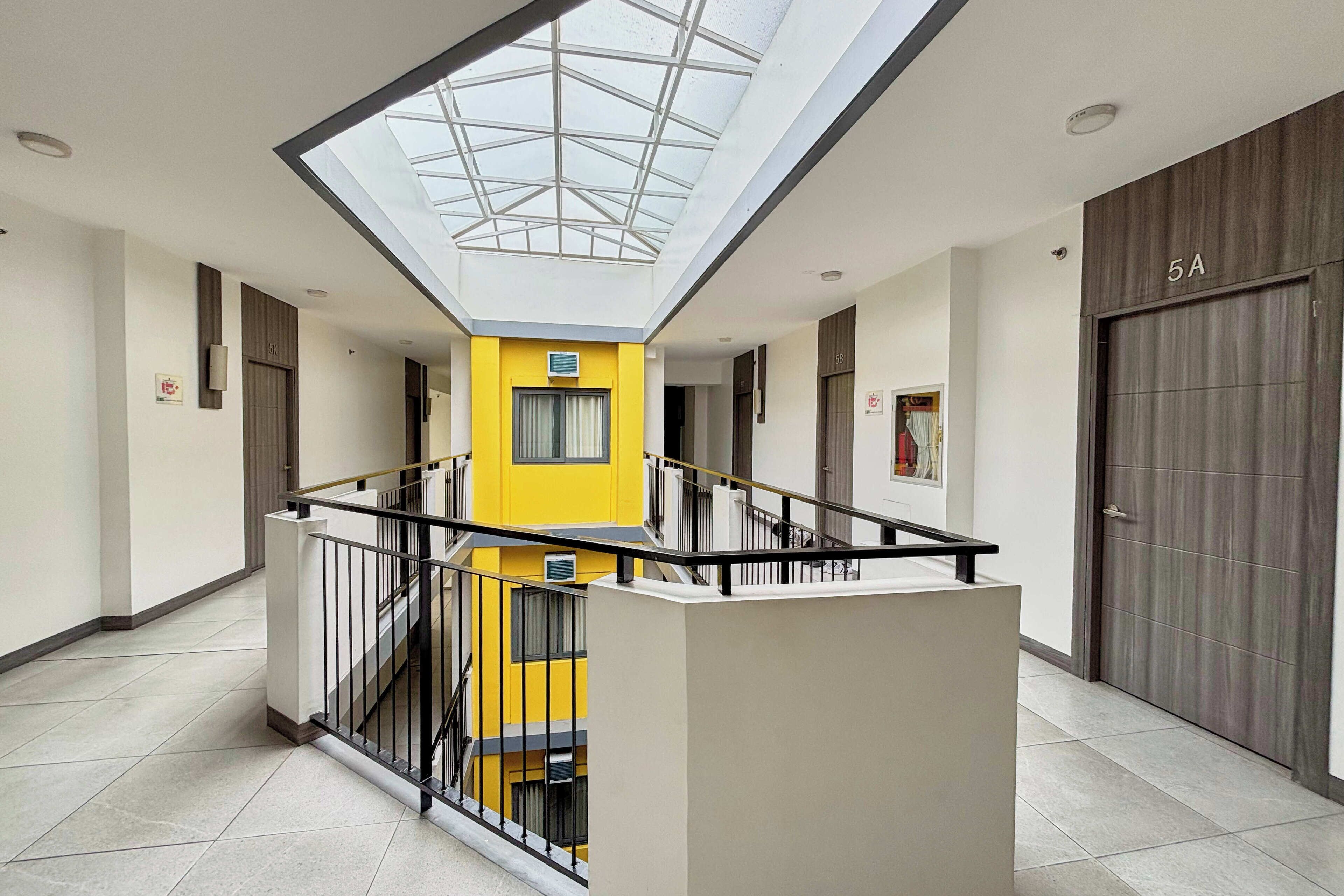 A modern interior with a central yellow column, a skylight, and a staircase.