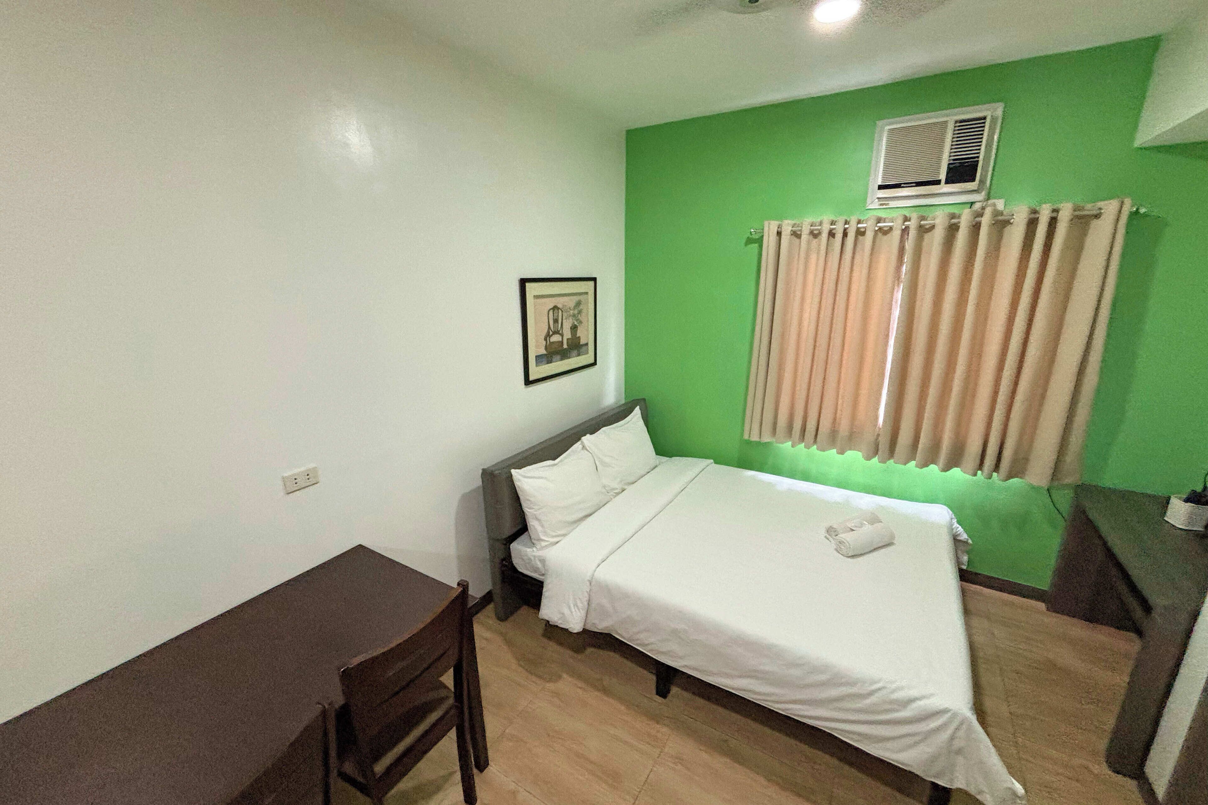 A room with a bed, a desk, and a chair.