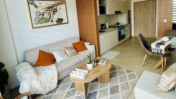 Een moderne woonkamer met een bank, salontafel en een eethoek met stoelen.