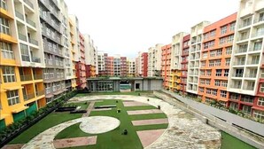 A residential complex with multiple apartment buildings, a central courtyard with a circular green area, and a paved walkway.