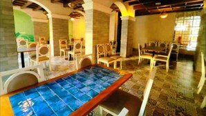 Un restaurante con una mesa azulada en el centro, rodeada de sillas blancas.