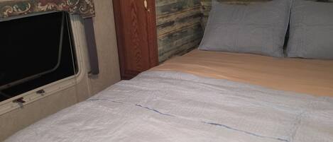 A bedroom with a bed, a window, and wooden cabinets.