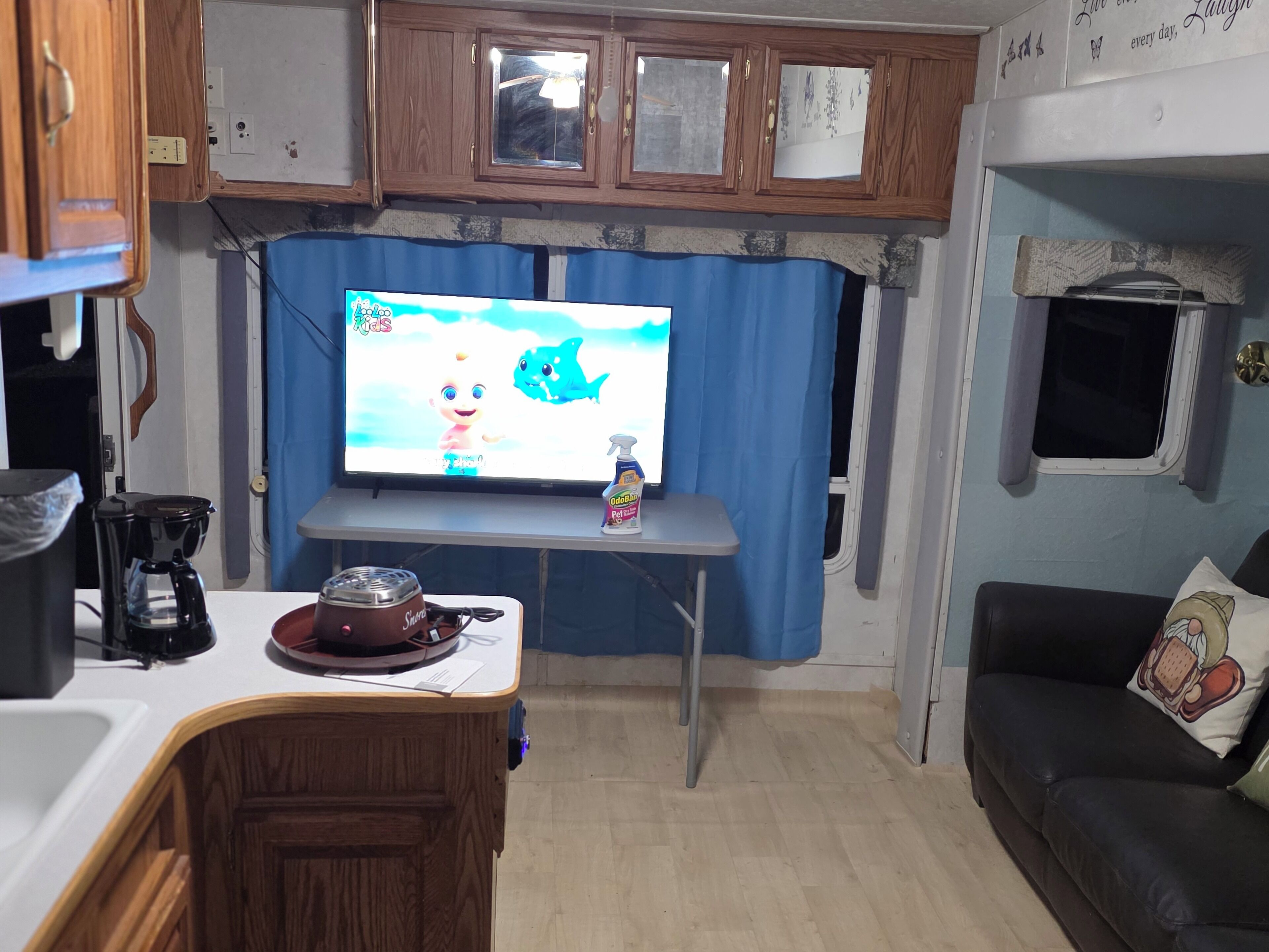 A compact living space with a kitchenette, a television, a coffee maker, and a pet food dispenser.