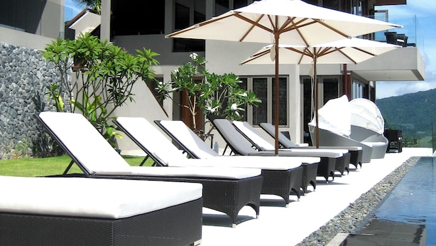Una casa moderna con piscina, sillas de descanso y sombrillas.