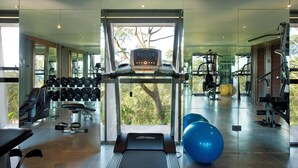 Un gimnasio moderno con cinta de correr, máquinas de pesas y pelotas de ejercicio.