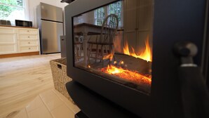 Een moderne keuken met een houtkachel, witte kastjes en een koelkast.
