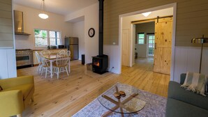 Een ruime woonkamer met een centraal gelegen open haard, houten vloeren en een eethoek.