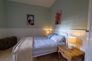 A bedroom with a bed, bedside table, lamp, and a trunk. - Ferntree Digs Cottage (Warburton)