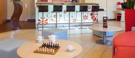 A modern lobby with a bar area, seating arrangements, and a chessboard.