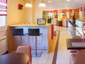 A modern restaurant with a central bar area, bar stools, and a seating area with tables and chairs. - Ibis Jouy en Josas Velizy (Jouy-en-Josas)