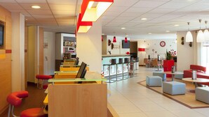 A modern hotel lobby with a bar area, seating, and a reception desk. - Ibis Jouy en Josas Velizy (Jouy-en-Josas)