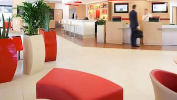 Eine moderne Hotelhalle mit einer Rezeption, Sitzbereichen und einer Bar.