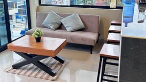 Un salon moderne avec un canapé, une table basse et une grande fenêtre donnant sur la ville.