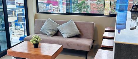 A modern living room with a sofa, a coffee table, and a large window offering a city view.