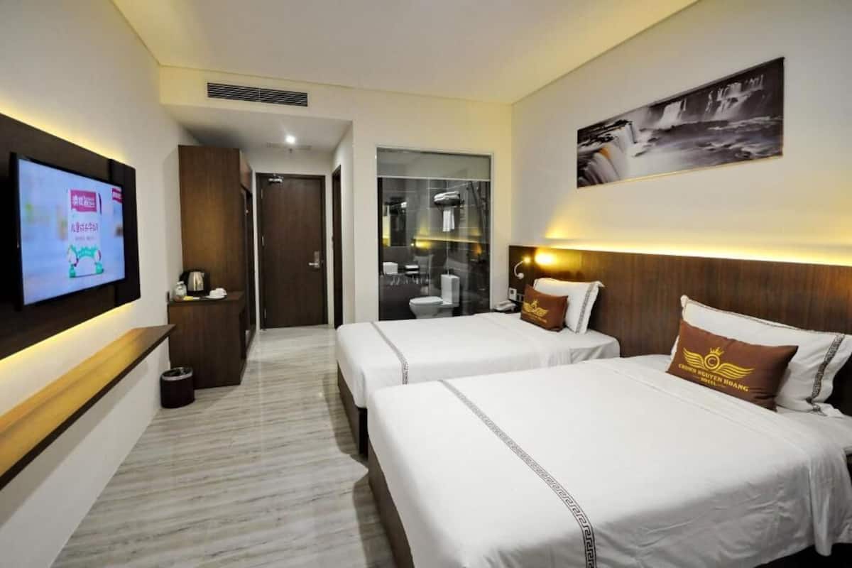 Een hotelkamer met twee bedden, een televisie, een badkamer en een douche.