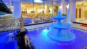 A hotel lobby with a fountain, seating area, and a glass entrance.