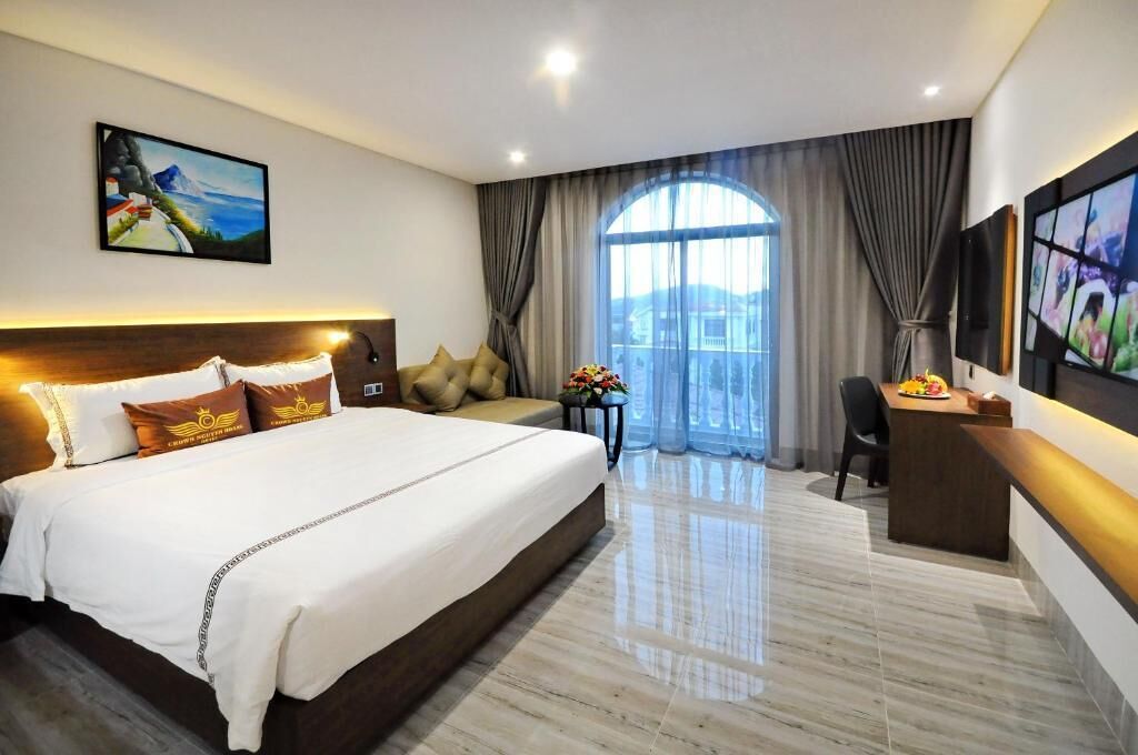 A hotel room with a large bed, a desk, a chair, and a TV.